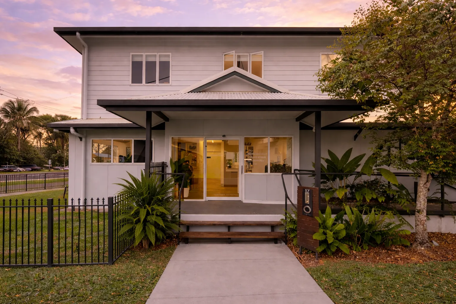 Sohma House entrance at sunrise — a white Queenslander with tropical garden