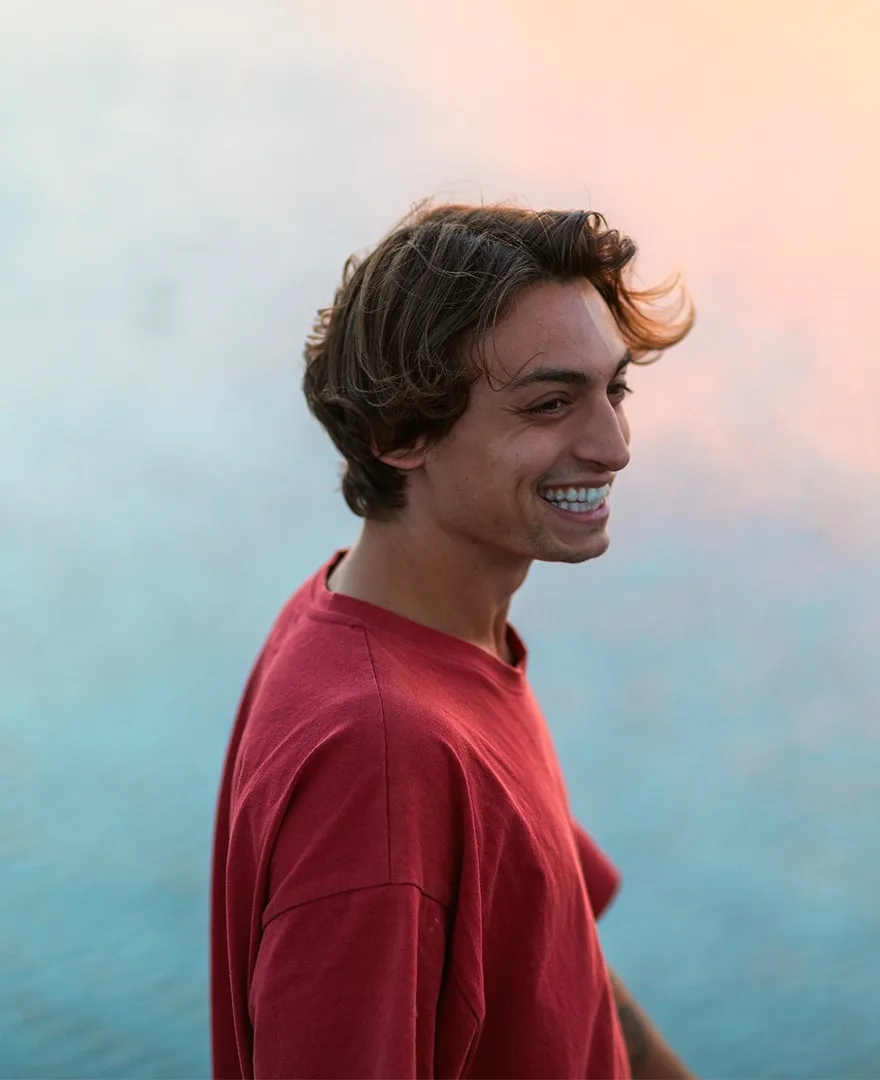 Cameron Rosin, founder of Sohma House, smiling in a red T-shirt against a soft evening sky