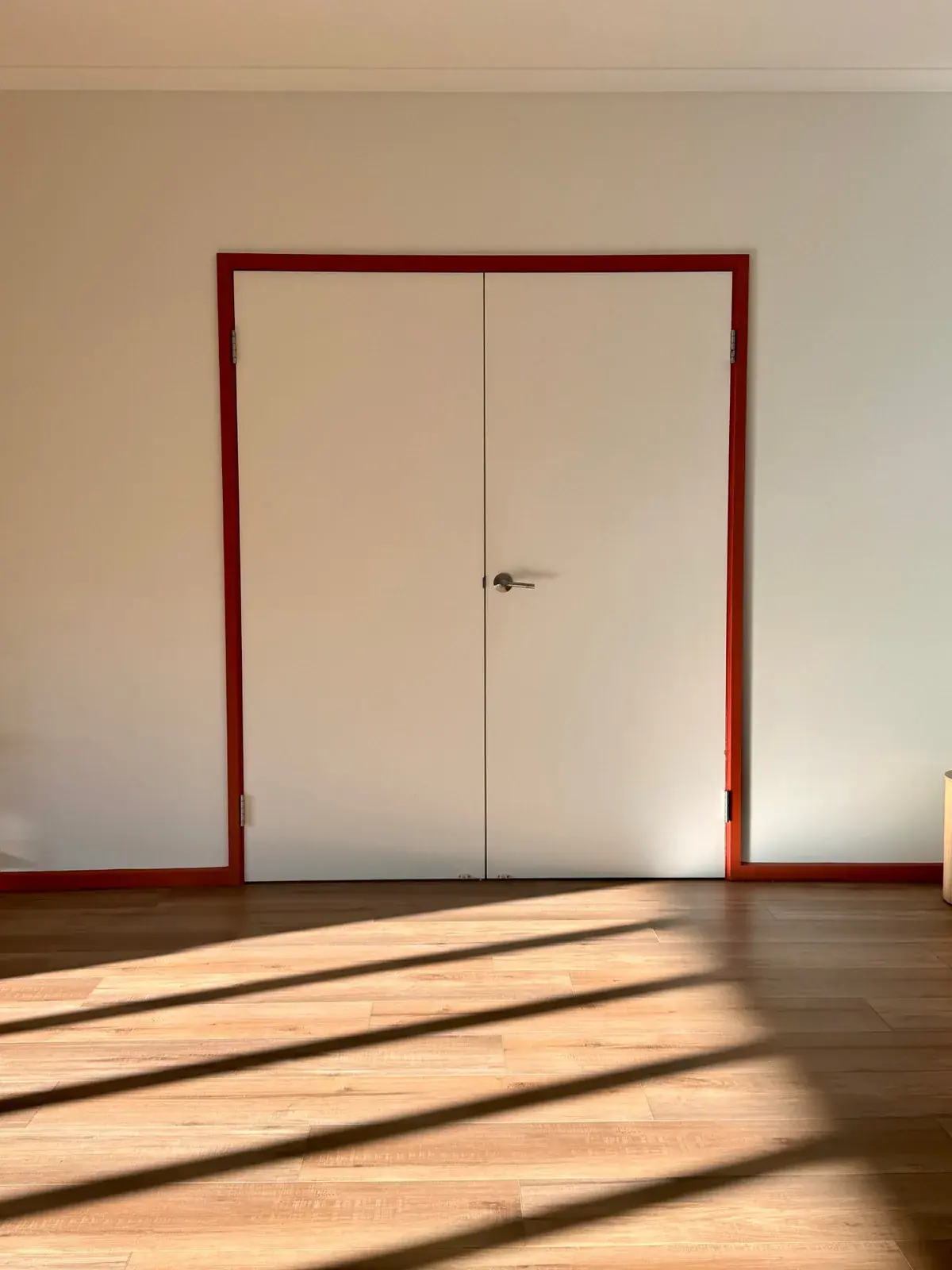 White double doors in a red frame, with window light across the floor