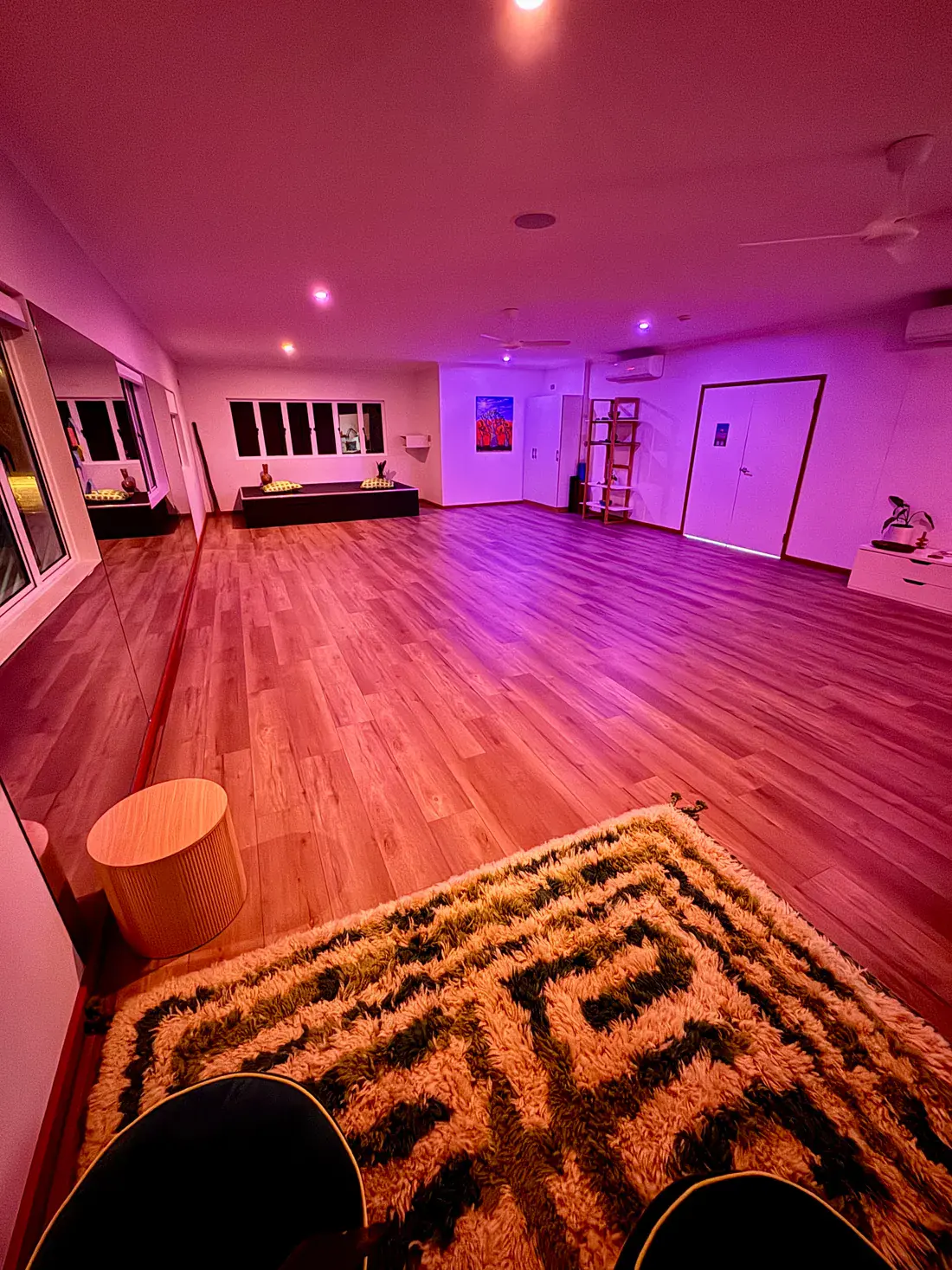 The studio upstairs in the evening, under warm pink light, with a shag rug on the timber floor