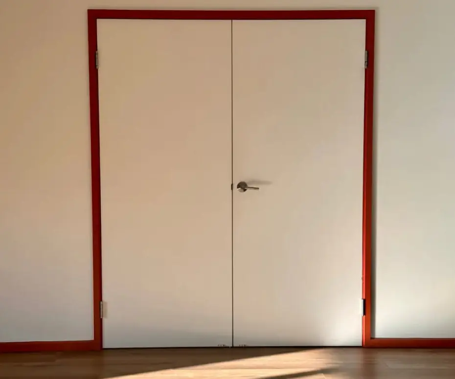 White double doors in a red frame, window light falling across a timber floor.